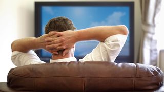 A relaxed man watching TV on a couch